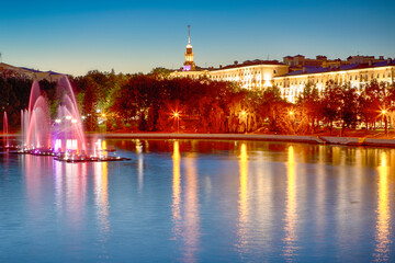 Colorful Illuminated Fountains on the Svisloch River During Summer Night Against Blue Sky Night View of Minsk City Center and Famous National Landmark of Belarus.