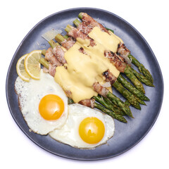 Healthy food - Asparagus wrapped with bacon and spices on a plate isolated on white background