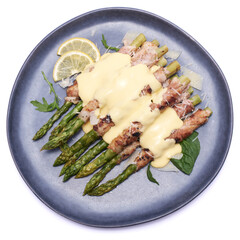 Healthy food - Asparagus wrapped with bacon and spices on a plate isolated on white background