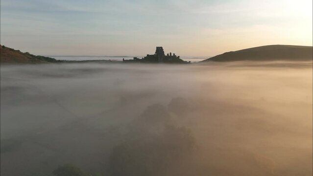 Corfe Castle surrounded by mist, stunning aerial view, Dorset, UK.