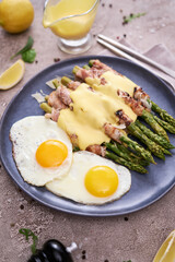 Healthy tasty breakfast - Asparagus wrapped with bacon and fried eggs on a plate