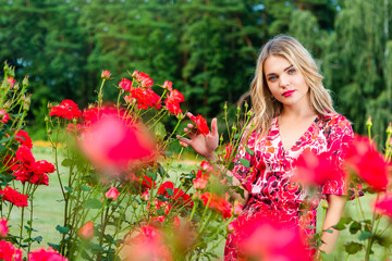 Beautiful spring girl in fragrant pink flowers in summer blossom park Woman in a blooming garden as Fashion, Cosmetics and Perfumes With Blond Hair