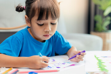 Cute little girl paints and tinkers with colored pencils and scissors