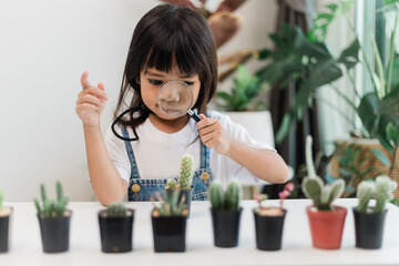 Kid gently touches the new stem of the cactus he grows with care nature education, Montessori, and...