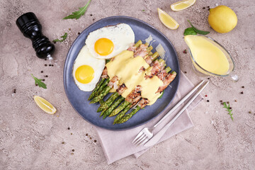 Healthy tasty breakfast - Asparagus wrapped with bacon and fried eggs on a plate