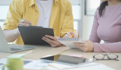 Two young business people sitting in modern office and discussing project strategy together.