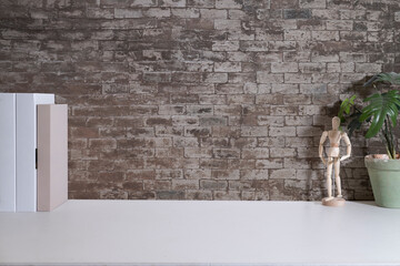 Stylish workplace with books, houseplant and wooden mannequin on white table. Copy space for your advertise text.