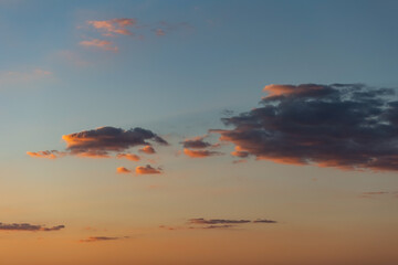 Sunset with few cumulus clouds, shining orange and pink at the horizon. Weather, clouds, temperature and meteorology.