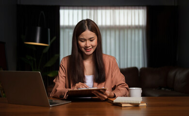 Charming young businesswoman using digital tablet while sitting in her contemporary office.