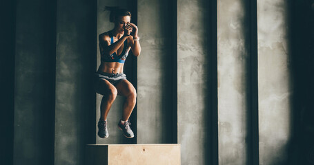 Fitness woman jumping on box while training at the gym,girl doing cross fit exercise. Sports...