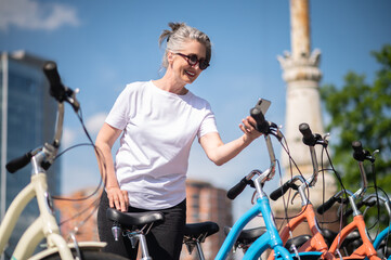 Obraz premium A woman in sportswear paying for bike rent online