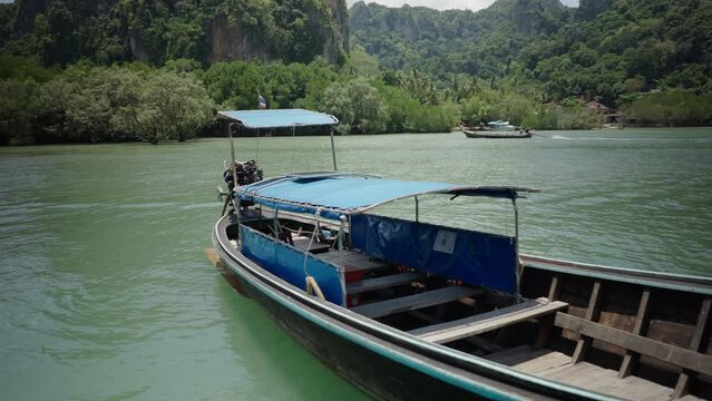 Thai long-tail passenger boat for travel guided island hopping tours floating anchored at Railay Beach, Thailand