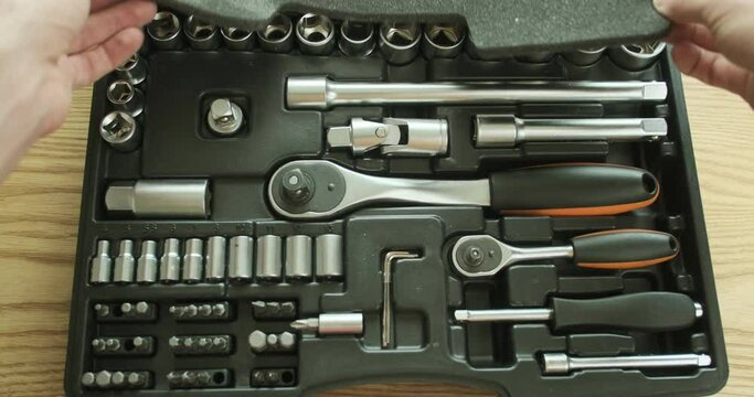 Man closes a plastic case with a set of ratchet sockets, socket wrenches, bits. A set of tools. First-person view