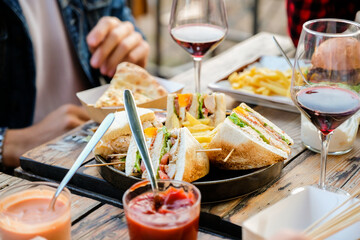 Close up of aperitif table. Friends dining together at brewery pub restaurant, with club sandwich,...