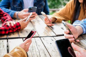 Group of friends checking social media on smartphones at restaurant or pub and ignoring each other...