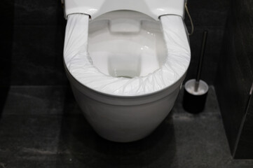 disposable cover pad on the rim of the toilet seat. wc hygiene system in public washroom. toilet...
