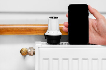 Male technician holding mobile phone using blank white screen mockup. Smart heating diagnostics by phone.