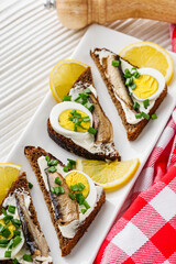 canapes with sprats on a white rustic wooden background