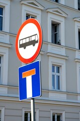 Vertical of a dead end and no bus sign in front of a building.