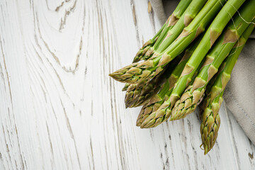 raw green asparagus on a white rustic wooden background