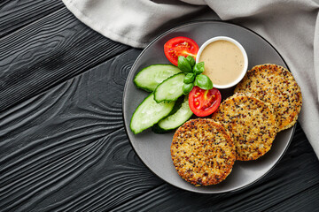 quinoa cutlet with vegetables on a black wooden rustic background