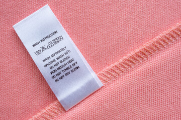 White laundry care washing instructions clothes label on pink cotton shirt