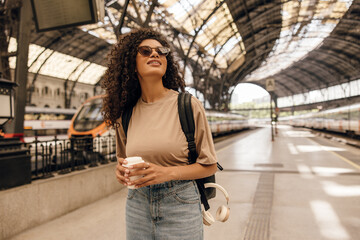 Beautiful young african woman looking on digit display searching her train to travel. Brunette...