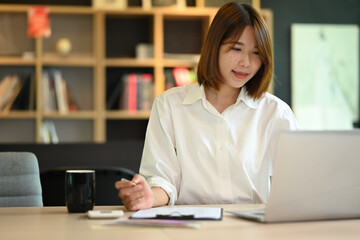 Obraz premium Asian woman creative designer working on new project, checking online information on her laptop
