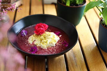 Dessert with forest fruit mousse, garnished with pistachio powder and flowers, selective focus.