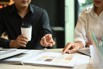 Fototapeta premium Two professional interior designers are working with color swatches and brainstorming for new project at co working space