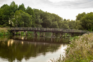 Old wooden bridge across the river, summer evening