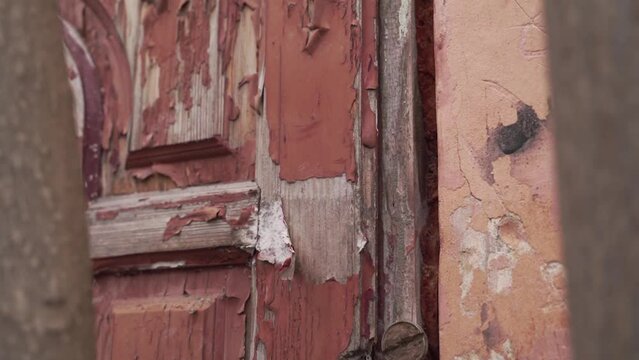 old wooden brown door on which the paint is peeling. close-up. facade of a house in which no one has lived for a long time. neglected housing