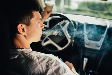 Man smoking a cigarette at the wheel of a car.