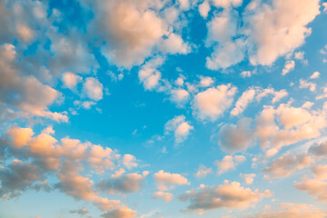 Blue sky background with white and pink cumulus clouds. Evening or morning time. Heaven concept. Dreams and imagination. Tranquil space. Natural landscape