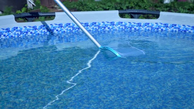 Cleaning the pool with a net. Maintenance and care of the pool.