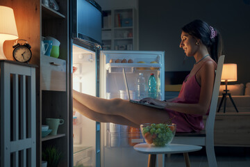 Woman cooling herself in front of the open fridge
