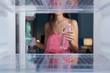 Woman taking a water bottle in the fridge
