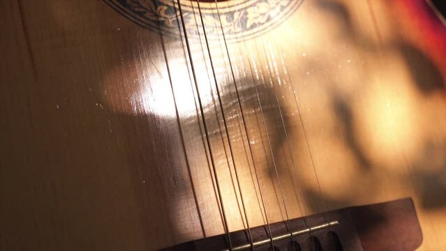 acoustic guitar body close-up, strings, bridge, resonator hole. smoky room. neck of an acoustic guitar. the rays of the sun are reflected on the guitar.
