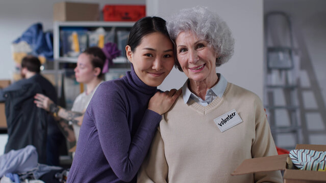 Portrait of multiethnic volunteers smile and hug looking at camera