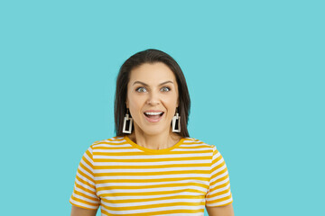 Omg. Joyful excited young woman with pleasantly surprised facial expression isolated on turquoise background. Close up portrait of smiling woman with wide open mouth and eyes can't believe her luck.