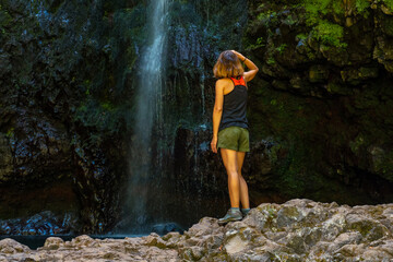 A young woman at the waterfall at the end of the waterfall trail at Levada do Caldeirao Verde, Queimadas, Madeira