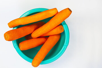 Several freshly peeled carrots in a blue bowl
