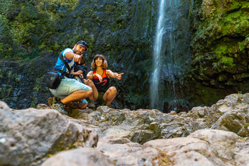 Naklejka na ściany i meble A family with their child in summer at the waterfall at Levada do Caldeirao Verde, Queimadas, Madeira
