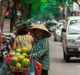 Obraz premium Vietnamese woman selling fruit and vegetables on the street. Traditional sale. Hanoi