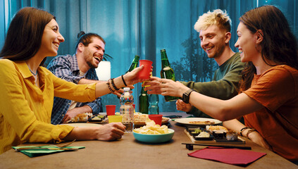 Happy friends toasting and eating together at home