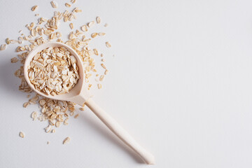 Oatmeal in a wooden spoon on a white background