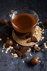 Hot oatmeal cocoa with pieces of chocolate in a transparent mug. Healthy drink