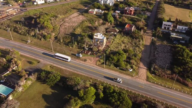 Aerial tracking shot of tour bus driving on main road iof Punta del Este at sunset light