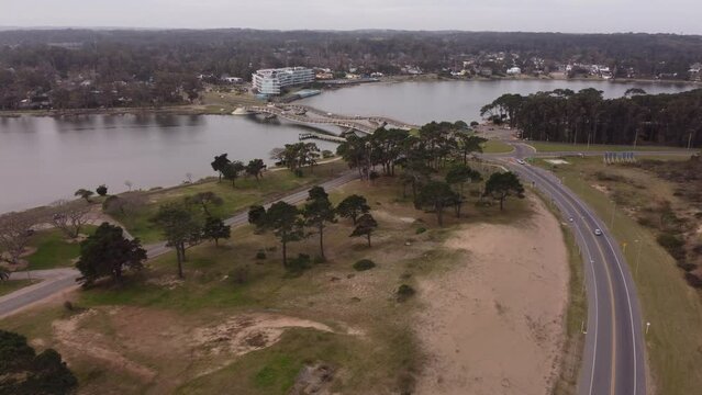 Aerial view of park, river and wavy Leonel Viera Bridge in Uruguay during cloudy day