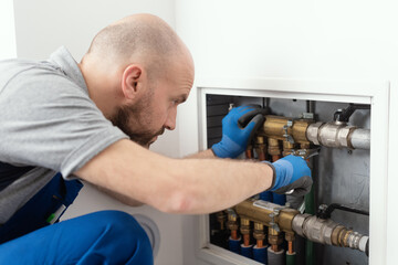 Professional plumber installing plumbing manifolds